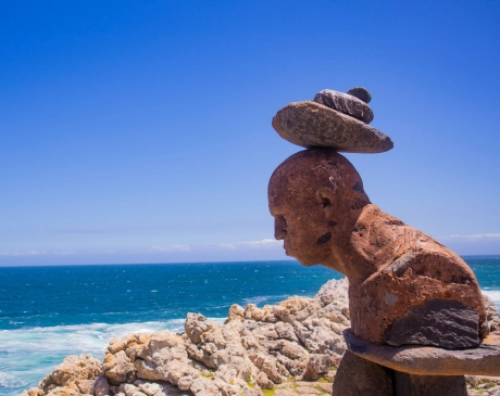A statue of a man balancing rocks on his head, located in Hermanus, South Africa.